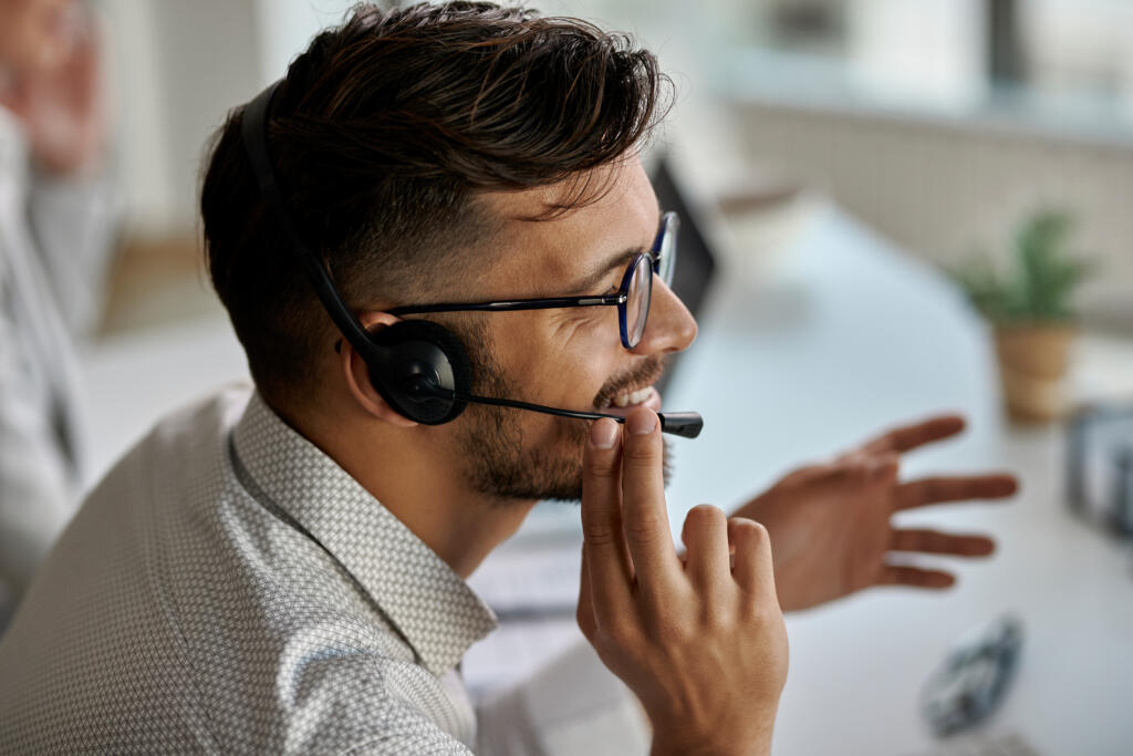 happy call center agent wearing headset while talking with clients working office 1 » StayBooked