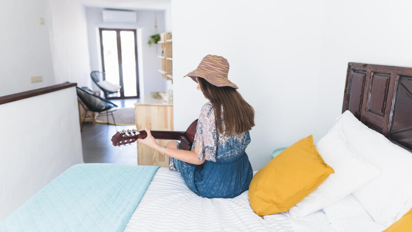 rear view woman sitting bed playing guitar » StayBooked